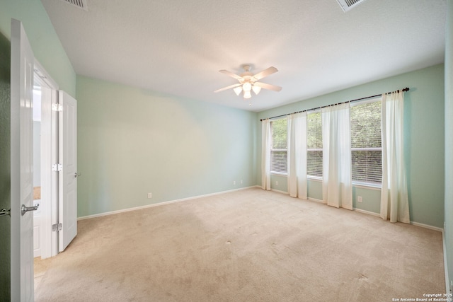 spare room featuring baseboards, light carpet, and ceiling fan