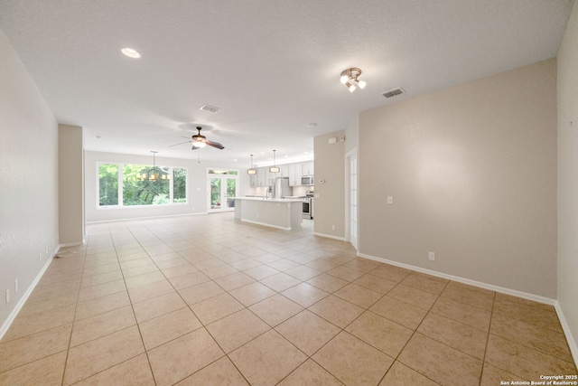 unfurnished living room featuring a ceiling fan, visible vents, baseboards, and light tile patterned flooring