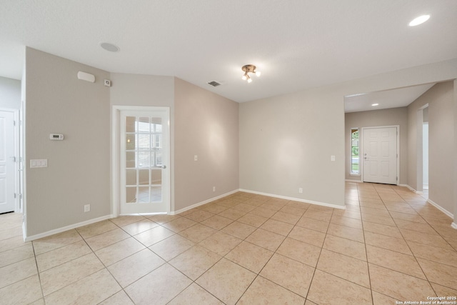 empty room with light tile patterned floors, baseboards, and visible vents