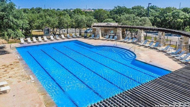 community pool with a patio area and fence