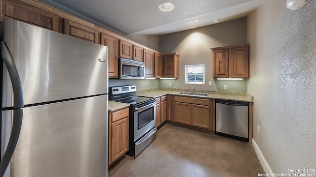 kitchen featuring a sink, finished concrete floors, a textured ceiling, baseboards, and appliances with stainless steel finishes