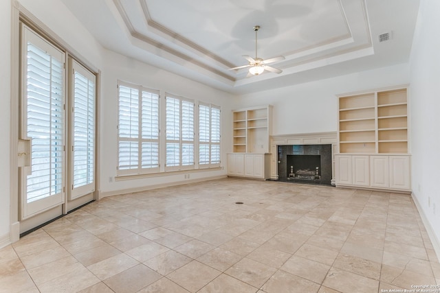 9 Waldenshire, San Antonio, TX 78209 - unfurnished living room featuring a ceiling fan, a tray ceiling, a fireplace, visible vents, and built in features
