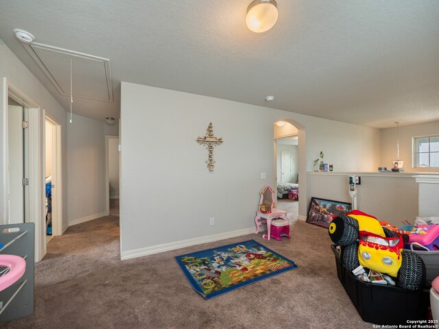 game room with attic access, carpet floors, arched walkways, and baseboards