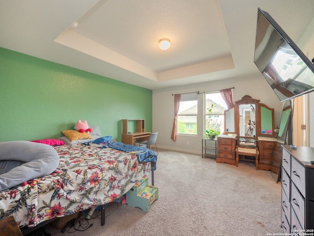 bedroom featuring a tray ceiling, light carpet, and baseboards