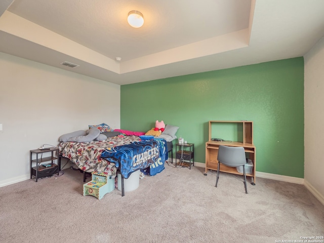 bedroom with carpet, visible vents, baseboards, and a raised ceiling