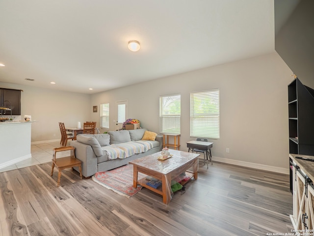 living room featuring light wood-type flooring, baseboards, and recessed lighting