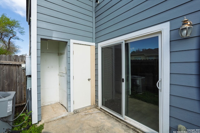 view of exterior entry featuring central AC unit and fence