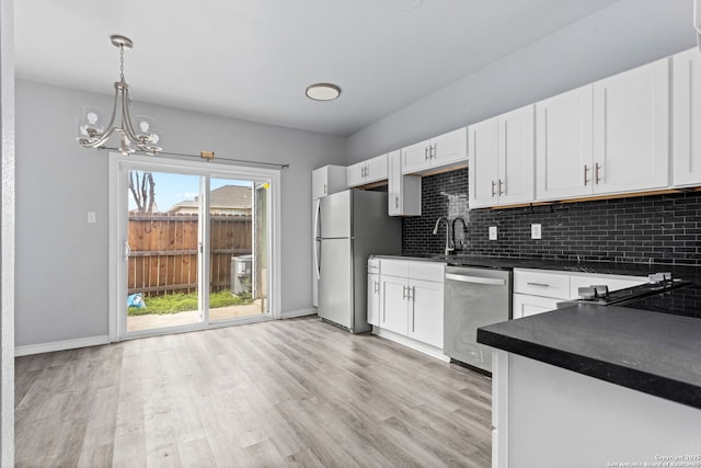kitchen with dark countertops, stainless steel appliances, light wood-type flooring, and decorative backsplash