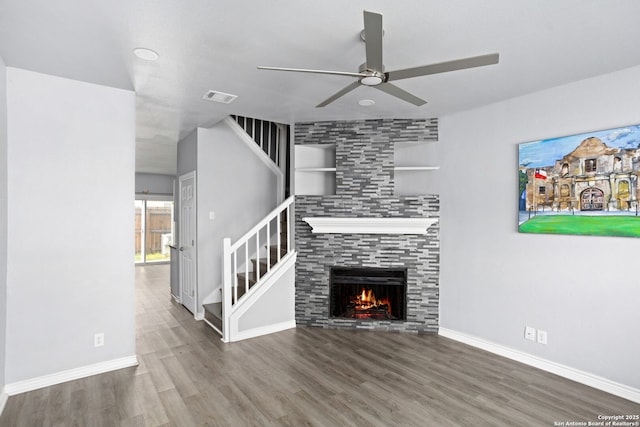 unfurnished living room with visible vents, ceiling fan, stairs, wood finished floors, and a fireplace