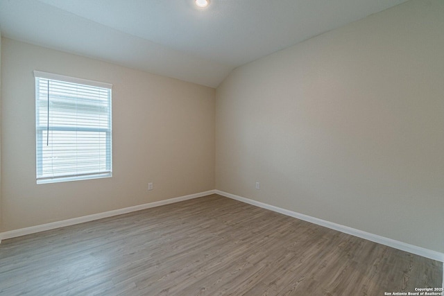 unfurnished room featuring vaulted ceiling, baseboards, and light wood-style floors