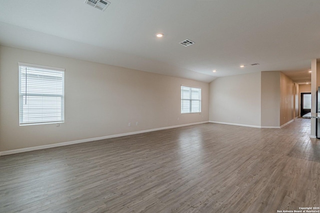 spare room featuring baseboards, visible vents, and wood finished floors