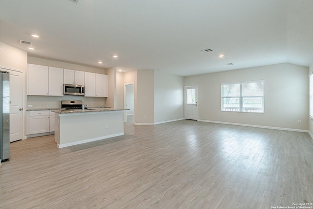 kitchen with stainless steel appliances, white cabinetry, light wood-type flooring, and visible vents