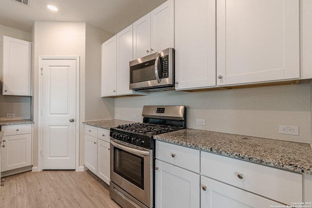 kitchen featuring white cabinetry, light wood-style floors, light stone counters, and appliances with stainless steel finishes