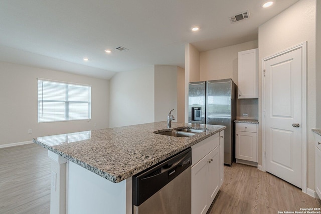 kitchen with light wood finished floors, a sink, visible vents, light stone countertops, and appliances with stainless steel finishes