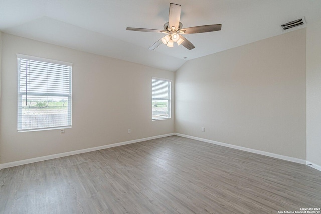 empty room featuring lofted ceiling, baseboards, ceiling fan, visible vents, and light wood-type flooring