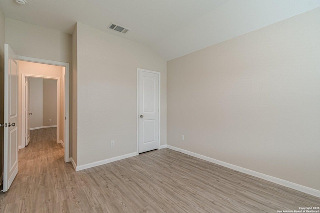 unfurnished bedroom with lofted ceiling, baseboards, visible vents, and light wood-type flooring