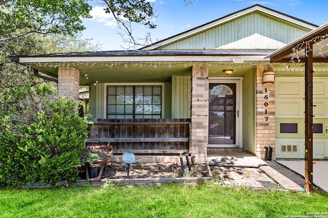 view of exterior entry featuring a porch and brick siding