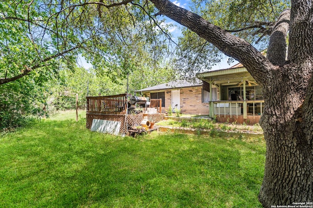back of house featuring a deck, brick siding, and a lawn