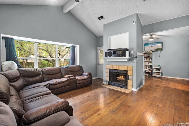 living area featuring hardwood / wood-style floors, high vaulted ceiling, a fireplace, ceiling fan, and beamed ceiling