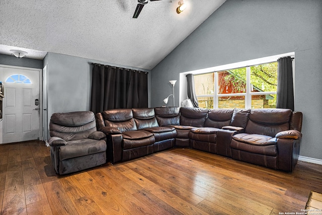 living area with a textured ceiling, a ceiling fan, wood-type flooring, and high vaulted ceiling