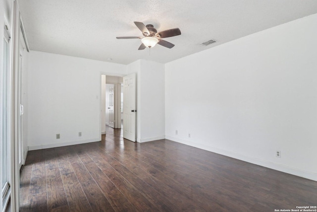 empty room with dark wood finished floors, visible vents, baseboards, and ceiling fan