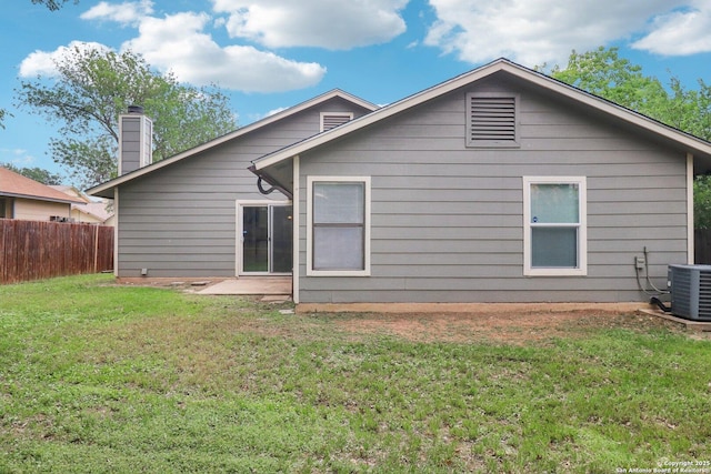 rear view of house with cooling unit, a yard, and fence