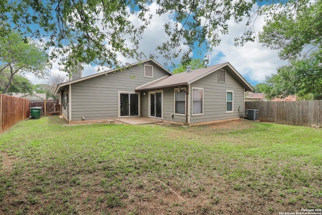 back of house featuring a chimney, central AC unit, a fenced backyard, a yard, and a patio area