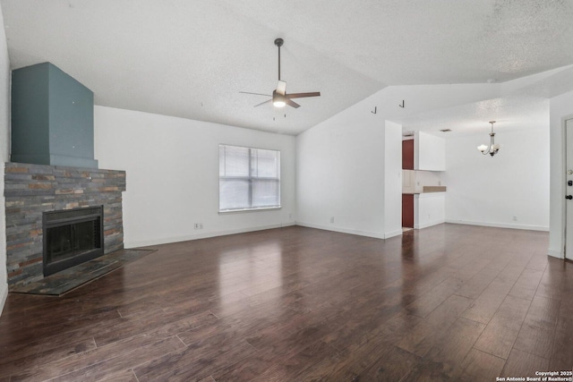 unfurnished living room featuring vaulted ceiling, a fireplace, dark wood-style floors, and ceiling fan with notable chandelier