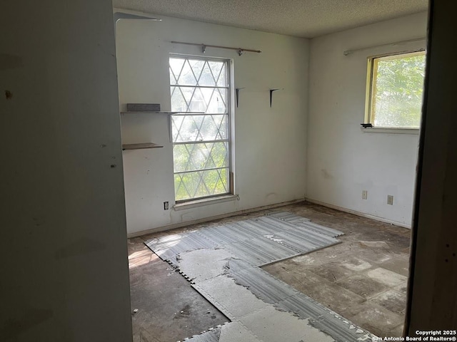 spare room featuring a textured ceiling and baseboards