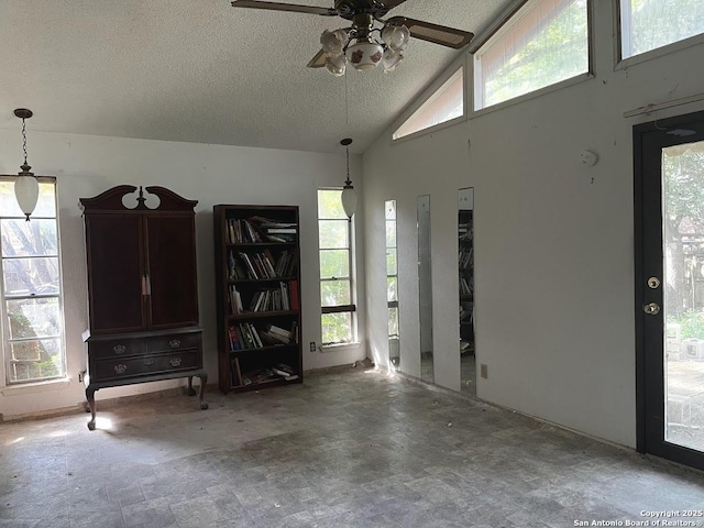 unfurnished living room with ceiling fan, a high ceiling, and a textured ceiling