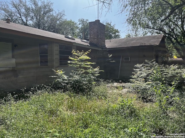 view of home's exterior featuring a chimney and a shingled roof