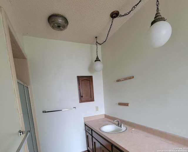 bathroom with a textured ceiling, a shower, and vanity