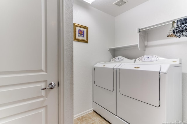 laundry room with washing machine and clothes dryer, light tile patterned floors, and baseboards