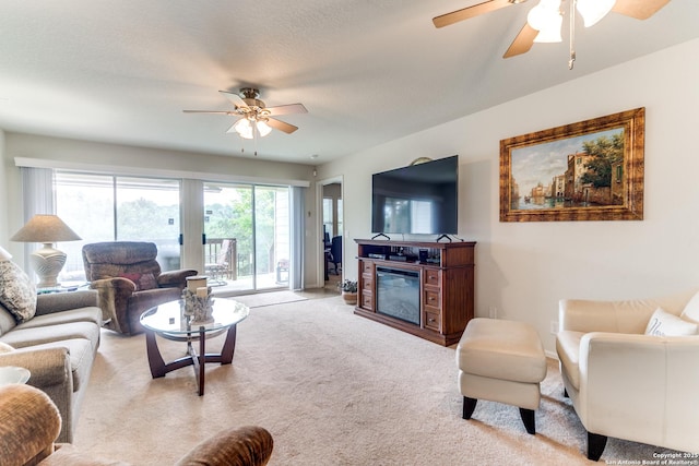 living room with a ceiling fan, light colored carpet, a glass covered fireplace, and baseboards