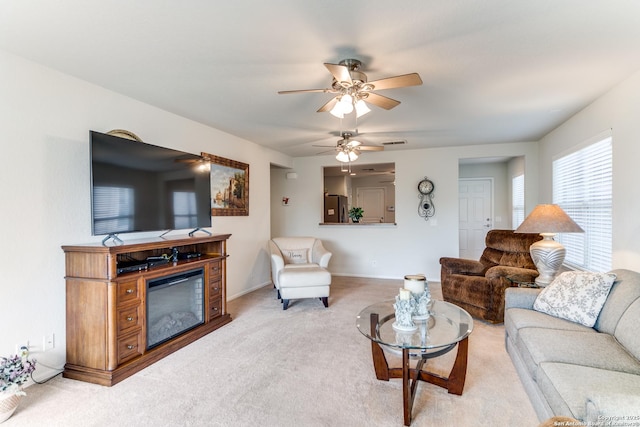 living room with light colored carpet, a ceiling fan, and baseboards