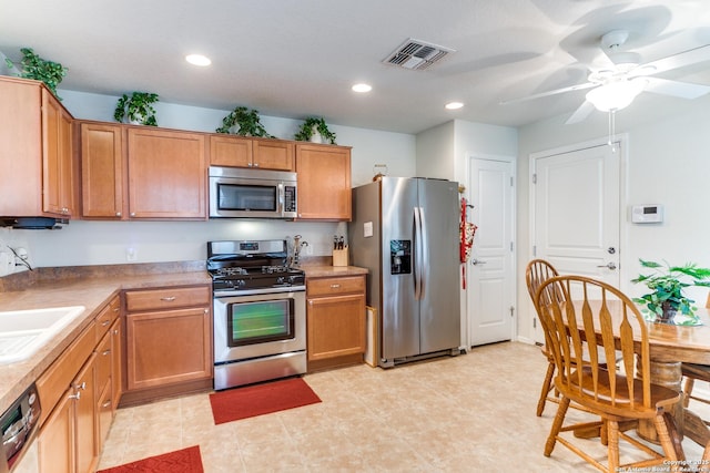 kitchen featuring appliances with stainless steel finishes, brown cabinetry, recessed lighting, a sink, and ceiling fan