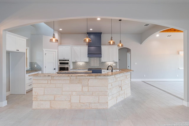 kitchen with baseboards, visible vents, arched walkways, backsplash, and double oven