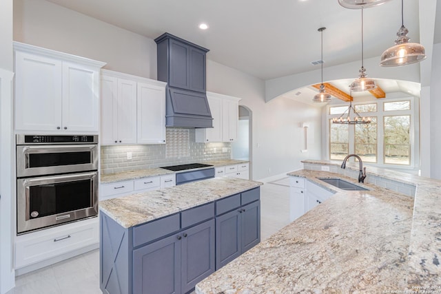 kitchen with an inviting chandelier, a sink, stainless steel double oven, arched walkways, and tasteful backsplash