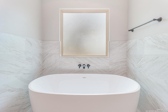 bathroom with a freestanding bath and tile walls