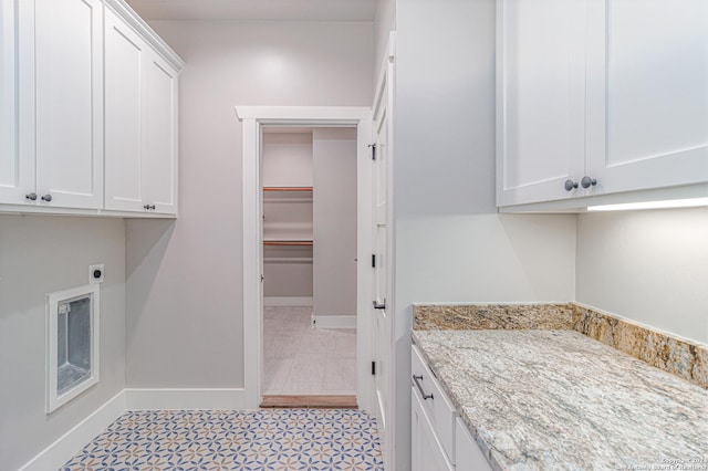 washroom featuring electric dryer hookup, cabinet space, and baseboards