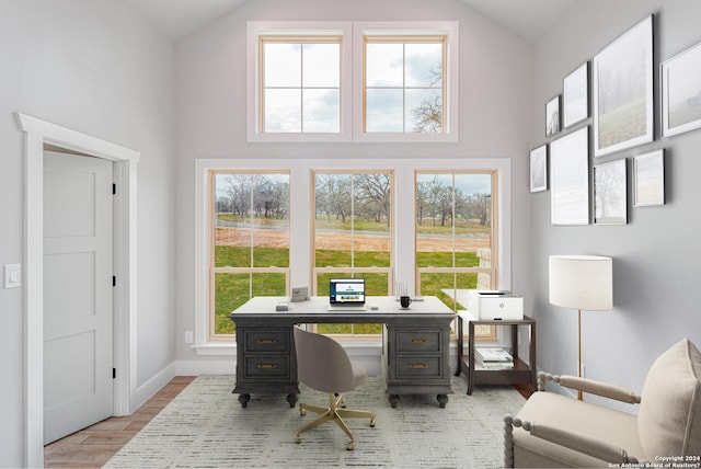 home office featuring baseboards, a wealth of natural light, light wood-style floors, and high vaulted ceiling