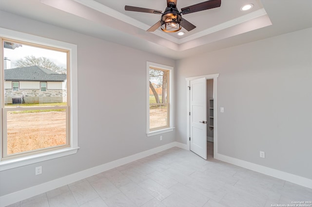 unfurnished room with a tray ceiling, crown molding, baseboards, ceiling fan, and recessed lighting