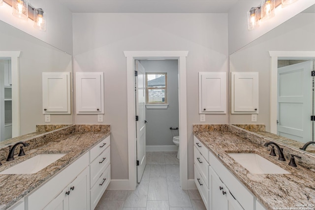 full bathroom with marble finish floor, baseboards, two vanities, and a sink