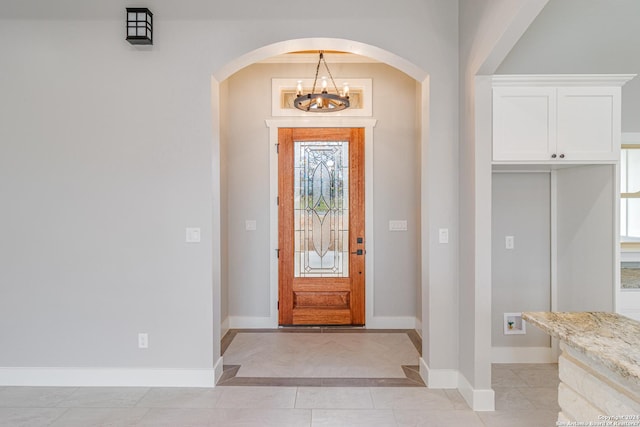 foyer entrance with a notable chandelier, baseboards, a healthy amount of sunlight, and arched walkways