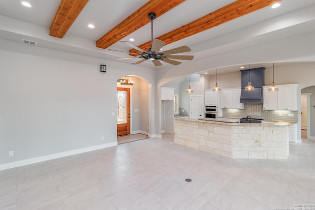 unfurnished living room featuring beam ceiling, visible vents, arched walkways, and recessed lighting