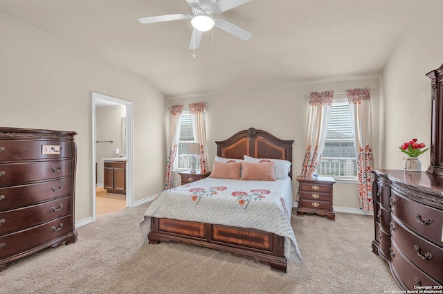 bedroom featuring vaulted ceiling, connected bathroom, light carpet, and baseboards