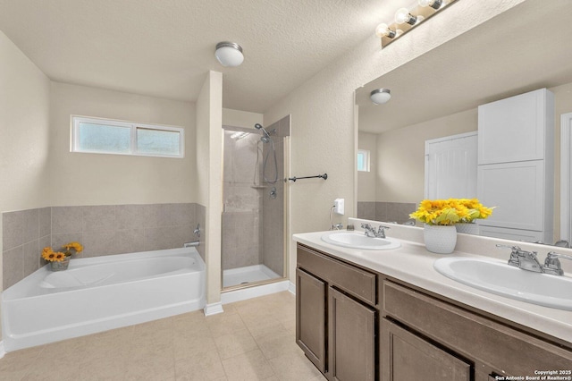 full bathroom featuring a shower stall, a bath, tile patterned floors, and a sink