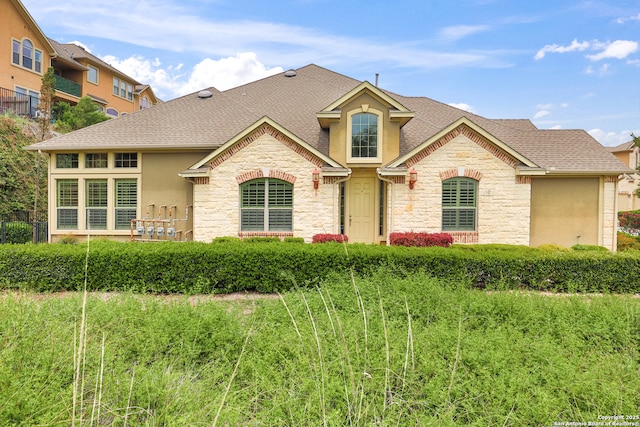 8250 Cruiseship Bay Unit, San Antonio, TX 78255 - view of front facade featuring stone siding, stucco siding, roof with shingles, and fence