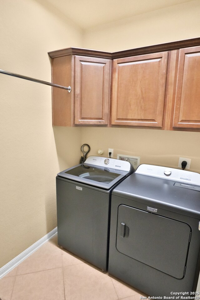8250 Cruiseship Bay Unit, San Antonio, TX 78255 - laundry area featuring washing machine and dryer, cabinet space, baseboards, and light tile patterned floors