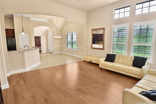 8250 Cruiseship Bay Unit, San Antonio, TX 78255 - living area featuring light wood-style flooring, baseboards, arched walkways, and ceiling fan with notable chandelier